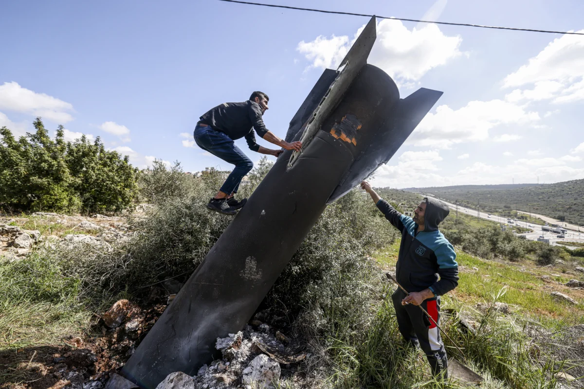 A Palestinian man climbs on the remnants of an Iranian missile that landed in the Israeli-occupied West Bank village of Hares on March 24, 2026. (Jaafar Ashtiyeh/AFP via Getty Images)