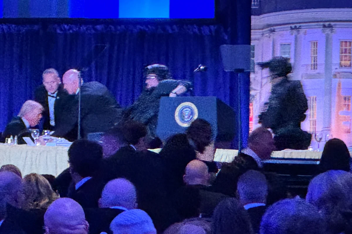 President Donald Trump (L) is seated on stage as U.S. Secret Service agents respond to take him from the ballroom after a shooting incident outside the ballroom during the White House Correspondents Dinner in Washington on April 25, 2026. (Mark Schiefelbein/AP Photo)