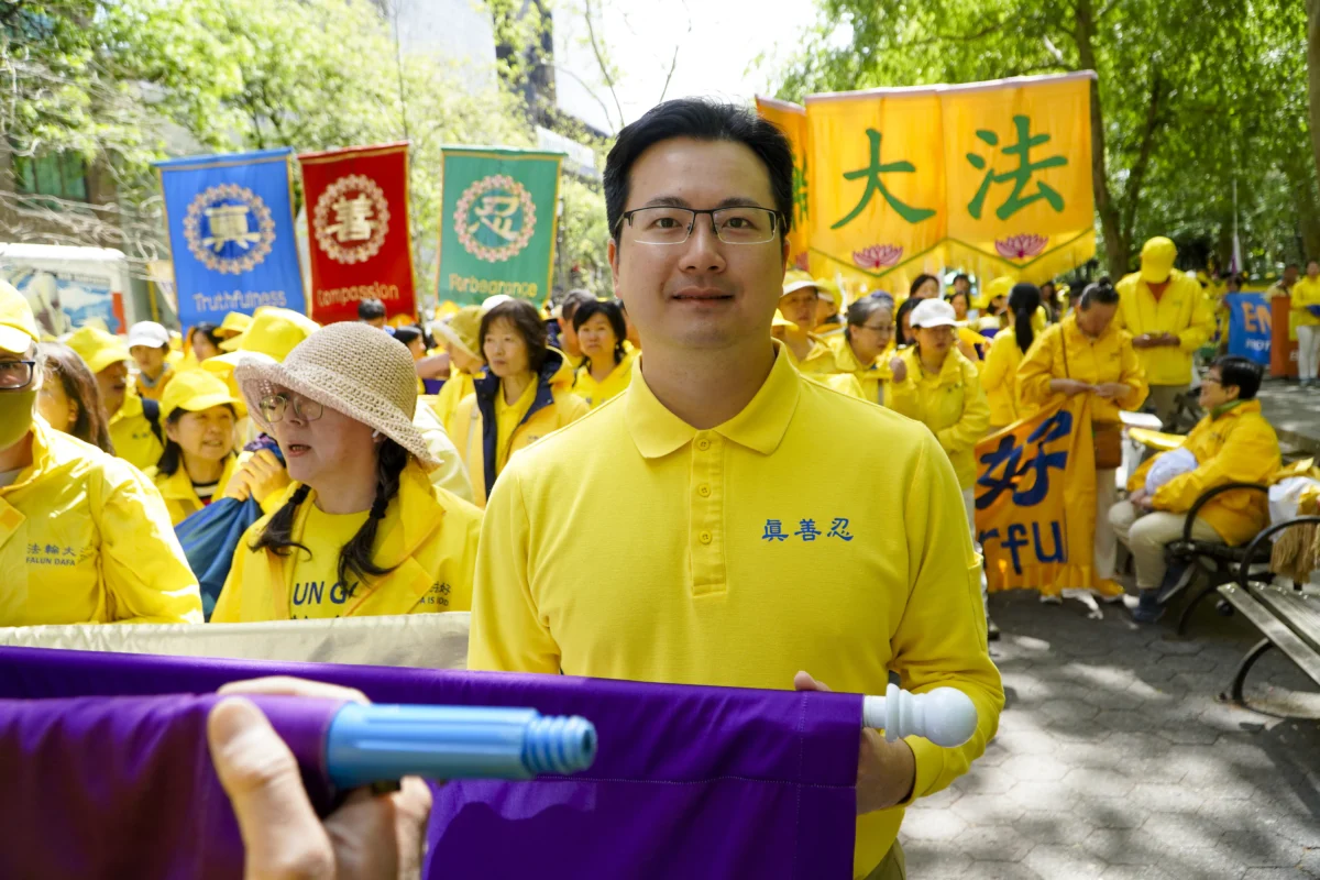 Hugh Huang, 34, originally from Hong Kong, Huang said practicing Falun Gong has helped him handle his anger better. He and other adherents of the practice lined up in Dag Hammarskjöld Plaza, to prepare for a parade celebrating World Falun Dafa Day on May 13, 2026. (Nicholas Zifcak/The Epoch Times)