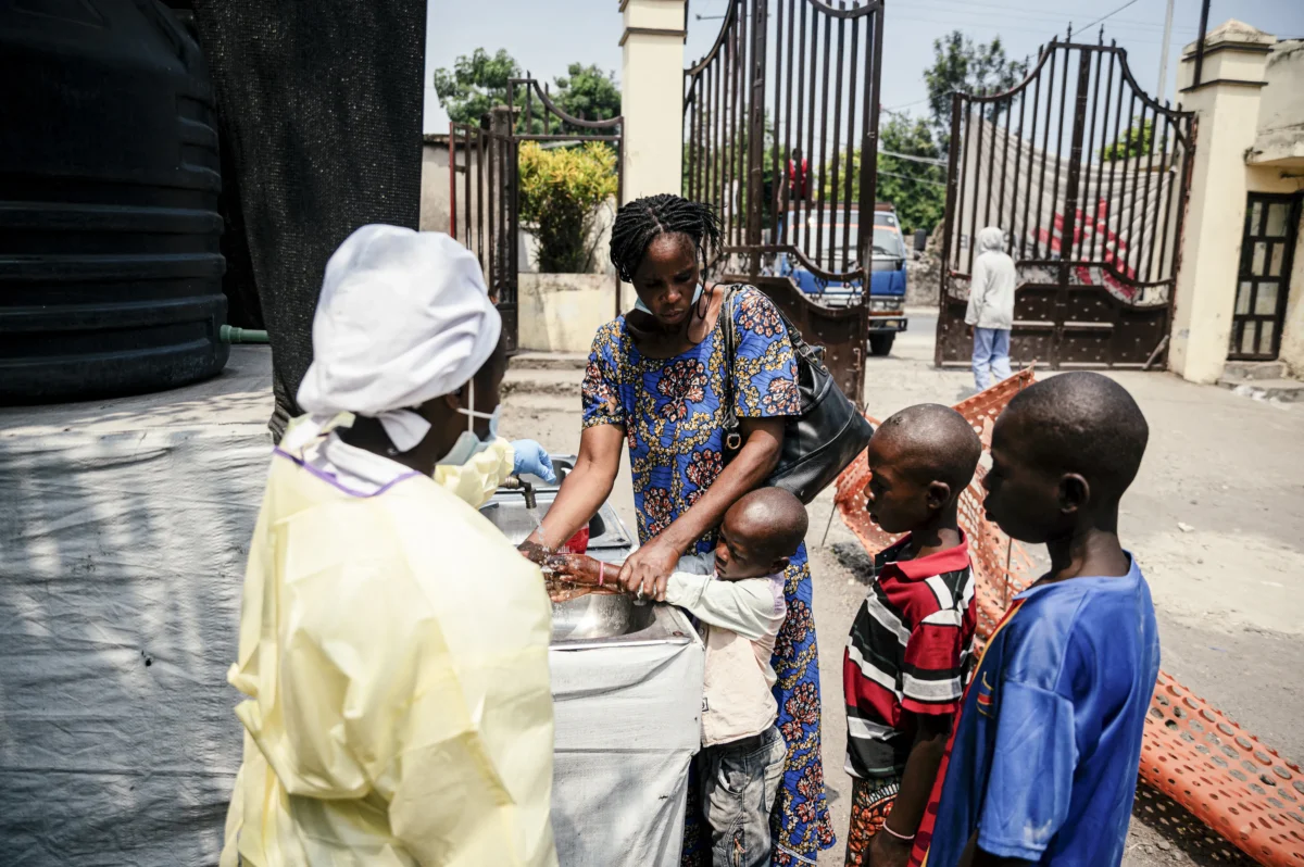 A mother helps her children wash their hands before entering Kyeshero Hospital in Goma on May 18, 2026. (Jospin Mwisha / AFP via Getty Images)