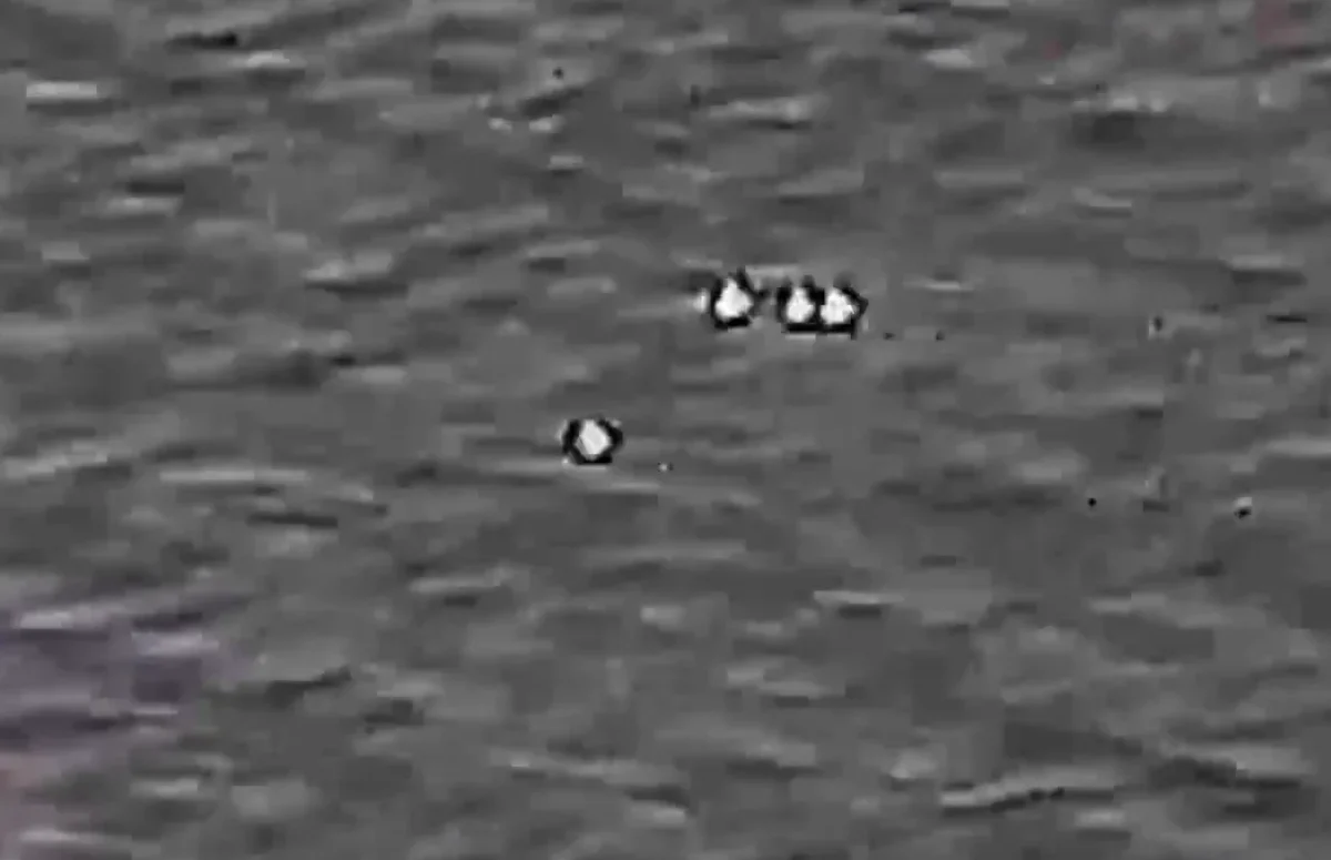 Four unexplained objects moving in the same direction in a screenshot from video. (Department of War)