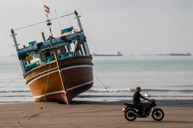 An Iranian man rides a motorcycle past a boat at Suru Beach in Bandar Abbas, Iran, on April 24, 2026. (Razieh Poudat/ISNA/AFP via Getty Images)