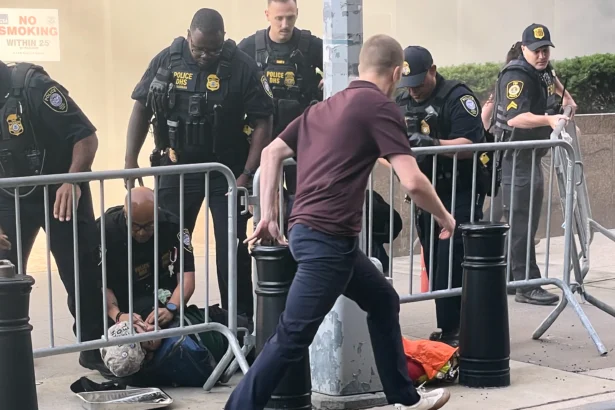 Several officers surround a person on the ground near the site of a fire at 26 Federal Plaza in lower Manhattan on July 20, 2026. (Robert Sullivan via AP)
