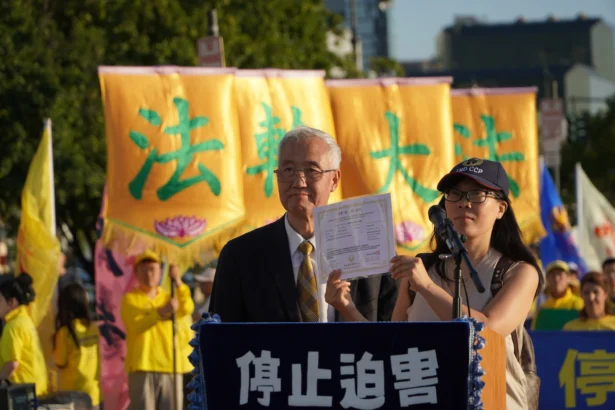 Hao Fangfang (R), holding up her certificate declaring her decision to quit the Chinese Communist Party and affiliated organizations, next to Wang Zhiyuan, chairman of the Global Service Center for Quitting the CCP, in New York on July 20. (Nicholas Zifcak/ The Epoch Times)