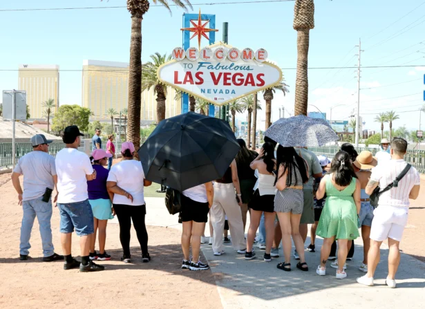 Visitors use umbrellas as shields from the sun and stand in a patch of shade while waiting in line to record images in front of the Welcome to Fabulous Las Vegas sign on the Las Vegas Strip as an extended period of above-normal heat continues, with high temperatures hitting 110 degrees, in Las Vegas on July 29, 2026. (Ethan Miller/Getty Images)