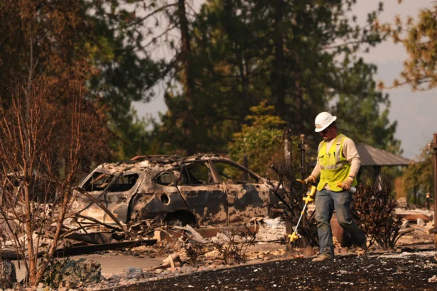 A worker with Avista moves through a property after a wildfire hit the northern part of Spokane, Wash., on Aug. 3, 2026. (Lindsey Wasson/AP Photo)