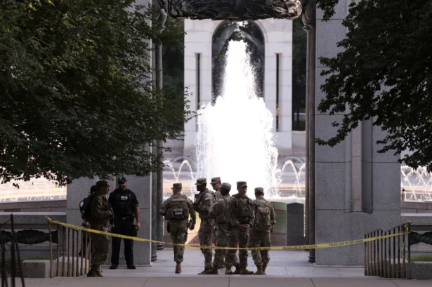 Members of the National Guard stand near the World War II Memorial, after the pool was reportedly vandalized with soap and graffiti in Washington on Aug. 13, 2026. (Kylie Cooper/Reuters)