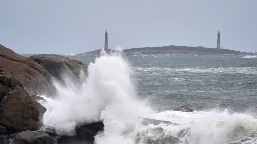Photo : ntd.com Surf breaks along the rocky coastline, with the twin lighthouses of Thatcher Island visible in the distance, during the
