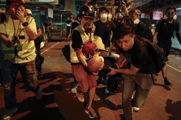 Medical staff and protesters carry an injured man as they face off with policemen near the Shum Shui Po police station in Hong Kong on Aug. 14, 2019. (Vincent Yu/AP Photo)