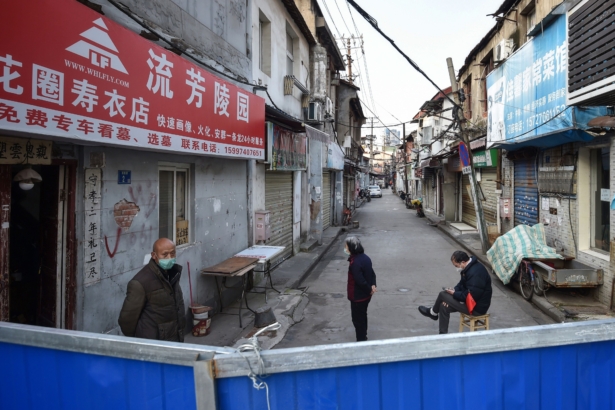 People standing on a street by a barrier to stop others from entering, in Wuhan in China's central Hubei Province on Feb. 23, 2020. (STR/AFP via Getty Images)