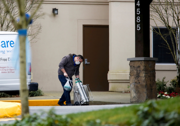 A man from a Bellevue Healthcare van wheels in oxygen tanks at an assisted living facility linked to several cases of COVID-19 outbreak in Redmond, Washington, on March 21, 2020. (Lindsey Wasson/Reuters)