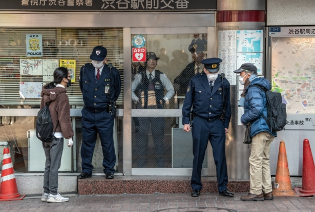 People wearing face masks ask directions from police officers who are also wearing face masks, at a police box by Shibuya crossing in Tokyo, Japan, on Feb. 27, 2020. (Carl Court/Getty Images)