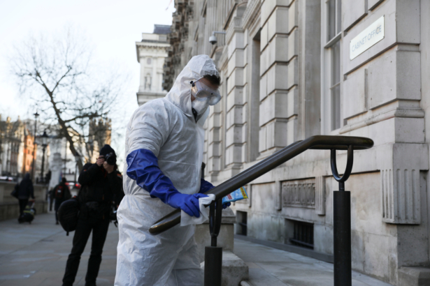 A man in a protective suit cleans a handrail as the number of COVID-19 grows in London, Britain, on March 16, 2020. (Simon Dawson/Reuters)