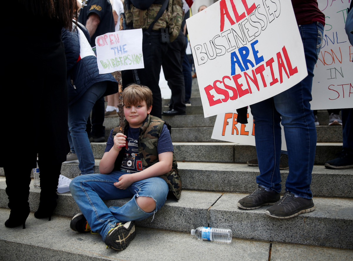 A boy holds a sign reading "Open the barbershop" as hundreds gather to protest against the state's extended stay-at-home order to help slow the spread of COVID-19 on the steps of the Capitol building in Olympia, Washington, on April 19, 2020. (Lindsey Wasson/Reuters)