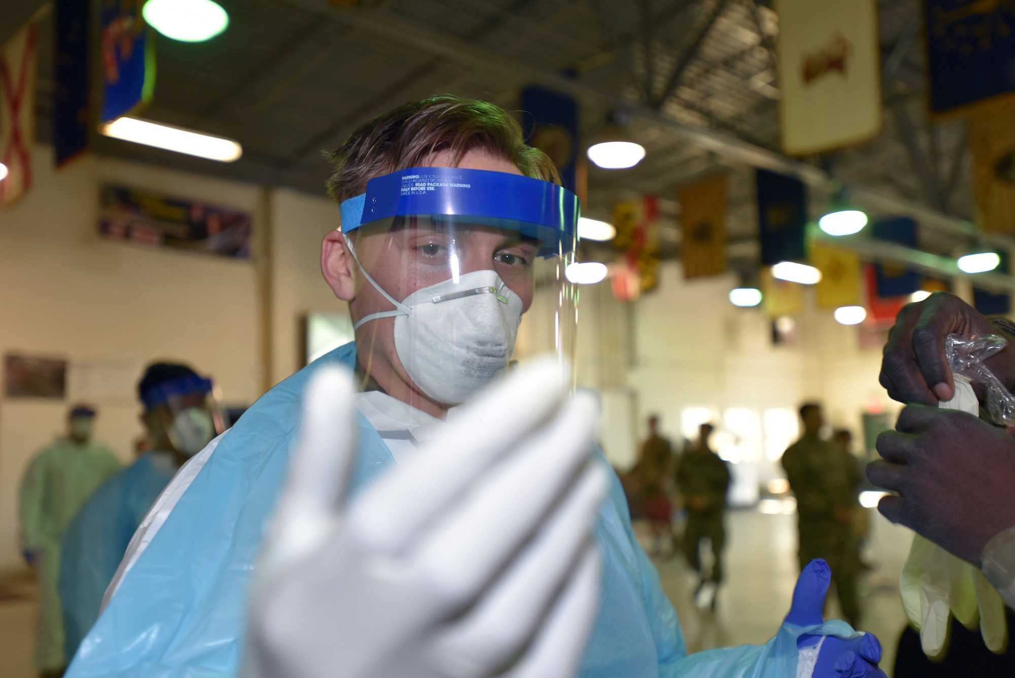 An army specialist inspects his glove fit while awaiting to forward deploy to a CCP virus testing site in Plymouth Meeting, Pa., on April 2, 2020. (Pennsylvania National Guard/Master Sgt. George Roach/Handout via Reuters)