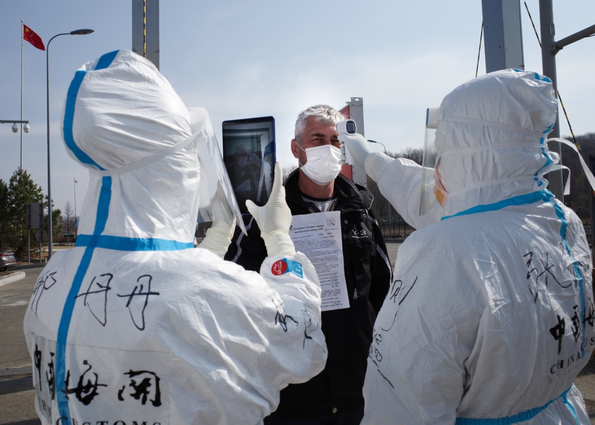 Staff wearing hazmat suits are checking the temperature of a driver at a customs checkpoint on the border with Russia at Suifenhe, China on May 1, 2020. (STR/AFP via Getty Images)