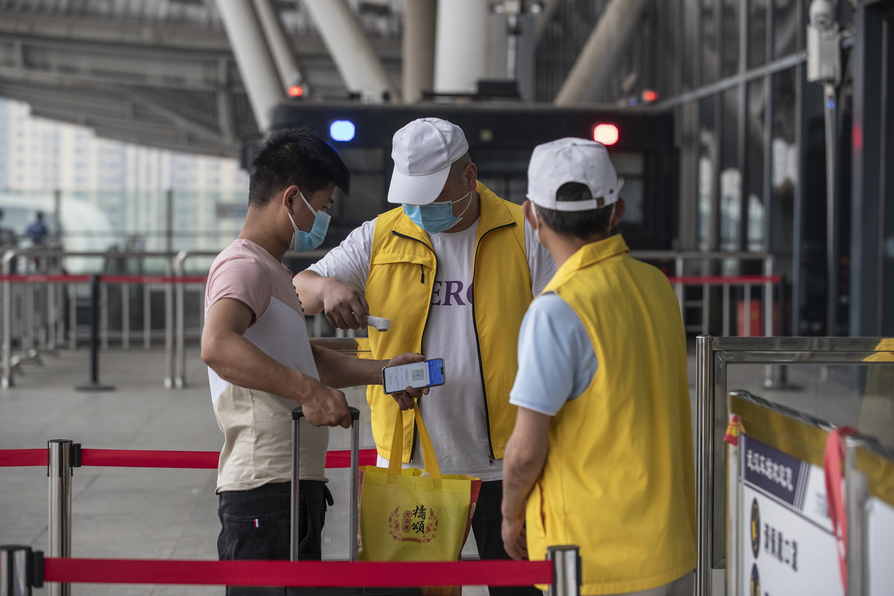 A staff member screens the body temperature of a passenger at the entrance of the Wuhan Railway Station in Wuhan, China, on May 28, 2020. (STR/AFP via Getty Images)