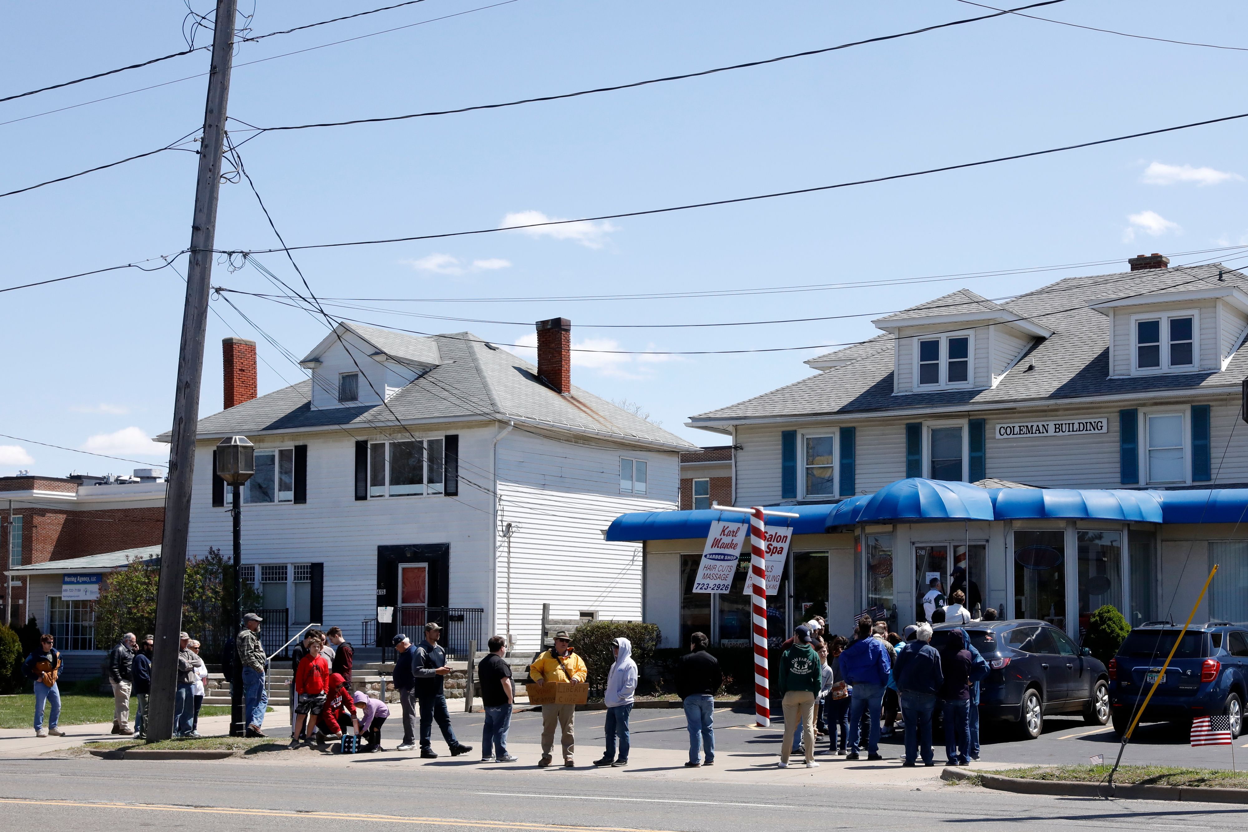 People wait in line to have their hair cut in front of the shop of Barber Karl Manke, who faces two misdemeanor charges for reopening his business despite state shutdown orders, in Owosso, Mich., on May 12, 2020. (Jeff Kowalsky/AFP via Getty Images)
