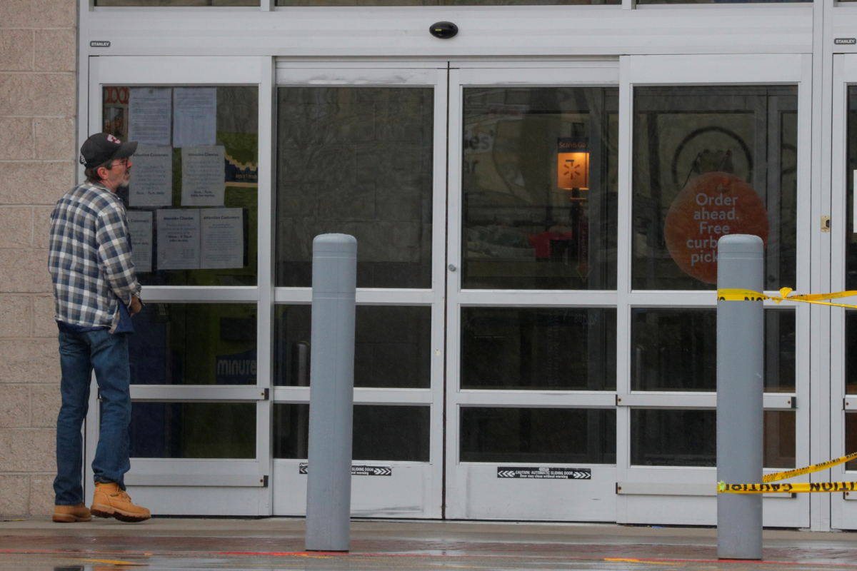 An employee talks on the phone and smokes outside to a Walmart Superstore temporarily closed by an order from the city after numerous employees tested positive for the CCP virus, which causes COVID-19, in Worcester, Mass., on April 30, 2020. (Brian Snyder/Reuters)