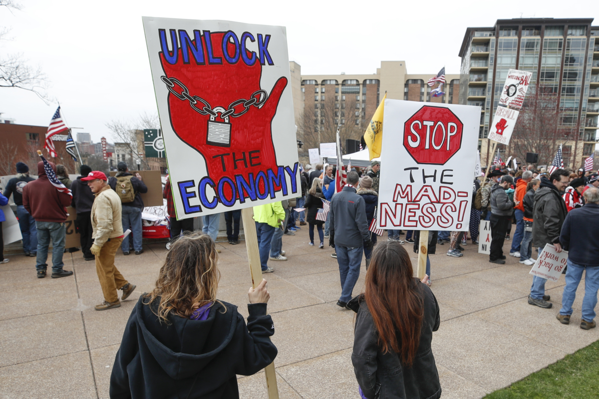 People hold signs during a protest against the CCP virus shutdown in front of the State Capitol in Madison, Wis., on April 24, 2020. (Kamil Krzaczynski/AFP via Getty Images)