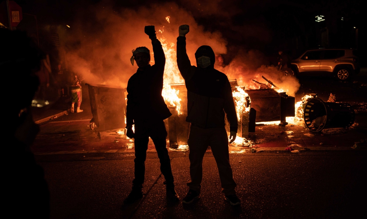 Demonstrators raise their fists as a fire burns in the street after clashes with law enforcement near the Seattle Police Departments East Precinct, in Seattle, Washington, on June 8, 2020. (David Ryder/Getty Images)