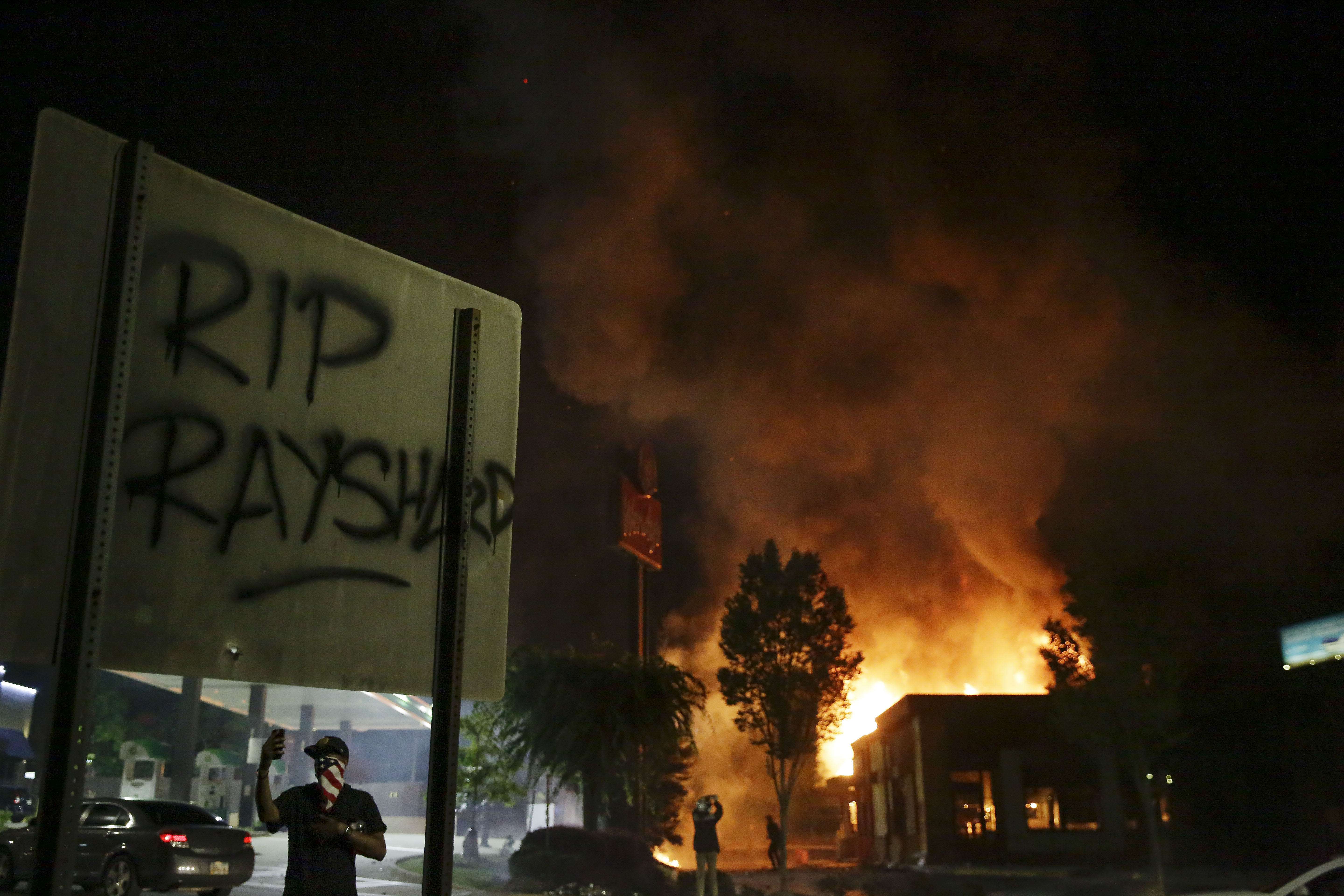 "RIP Rayshard" is spray-painted on a sign as flames engulf a Wendy's restaurant during protests in Atlanta, Ga., on June 13, 2020. (Brynn Anderson/AP Photo)