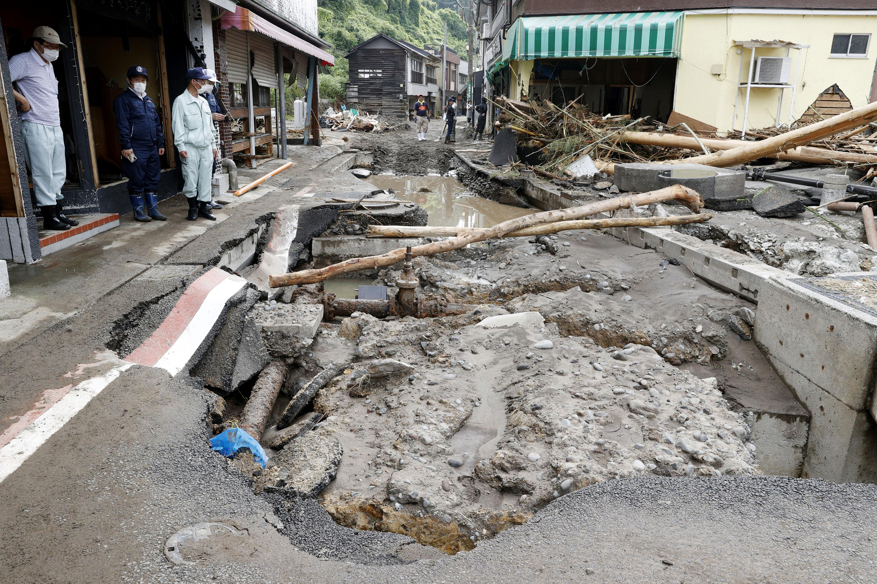 People stand near a road damaged by a heavy rain in Hita, Oita prefecture, southern Japan on July 9, 2020. (Kyodo News via AP)