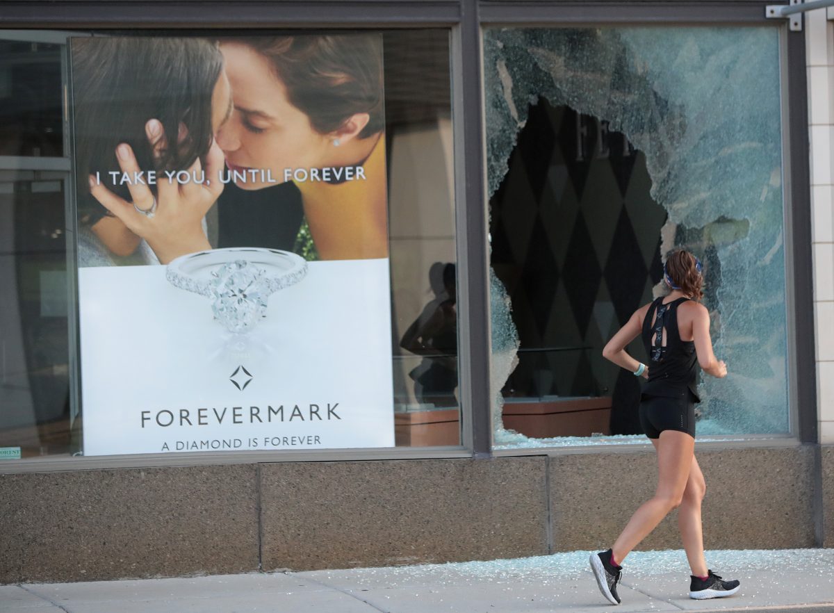 A jogger runs past a broken storefront window after parts of the city had widespread looting and vandalism, in Chicago, on Aug. 10, 2020. (Scott Olson/Getty Images)