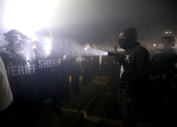 A protestor shines a flashlight in the direction of Kenosha County Sheriffs Deputies outside the Kenosha Police Department in Kenosha, Wis., late Aug. 23, 2020. (Mike De Sisti/Milwaukee Journal Sentinel via USA TODAY via Reuters)