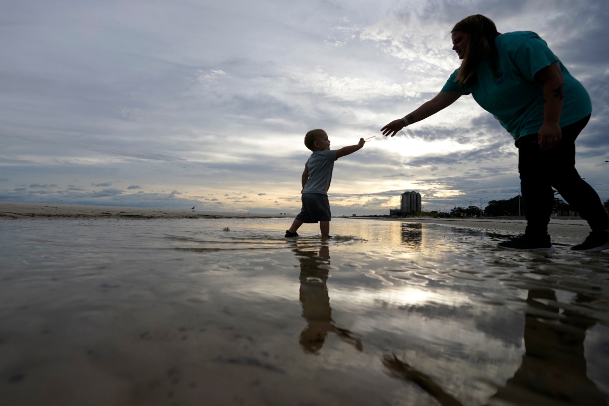 Nikita Pero walks with her 2-year-old son Vinny Pero, on the beach along the Gulf of Mexico in Biloxi, Miss., on Sept. 14, 2020. (Gerald Herbert/AP Photo)