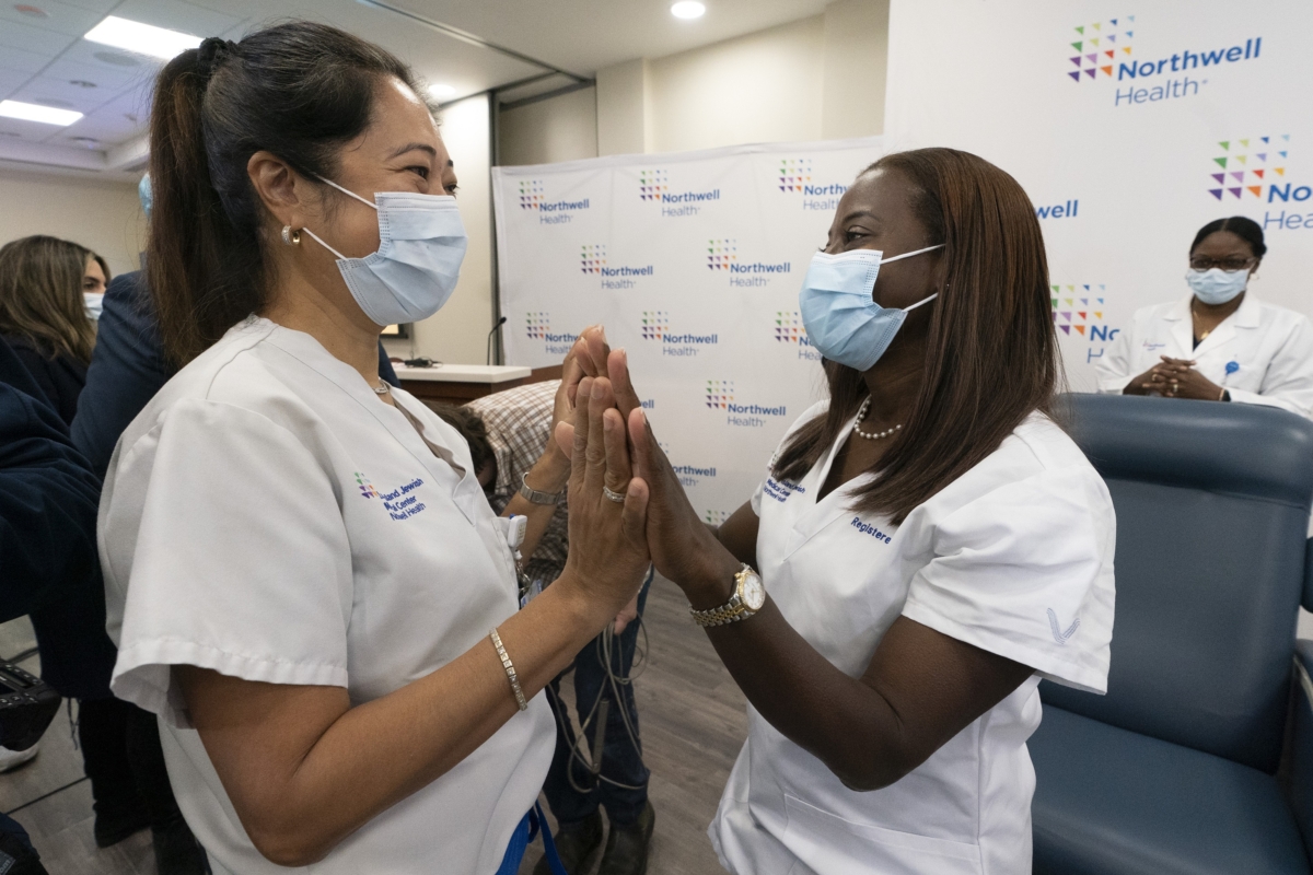 Nurse Annabelle Jimenez (L) congratulates nurse Sandra Lindsay after she is inoculated with the Pfizer-BioNTech COVID-19 vaccine at the Jewish Medical Center, in the Queens borough of New York, on Dec. 14, 2020. (Mark Lennihan/Pool/AP Photo)