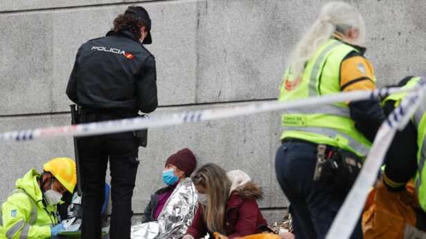 A police officer and medical personnel assist people