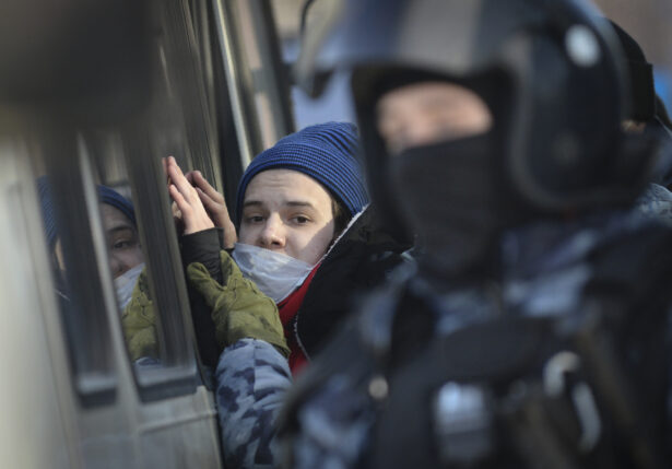 Police officers detain a young man