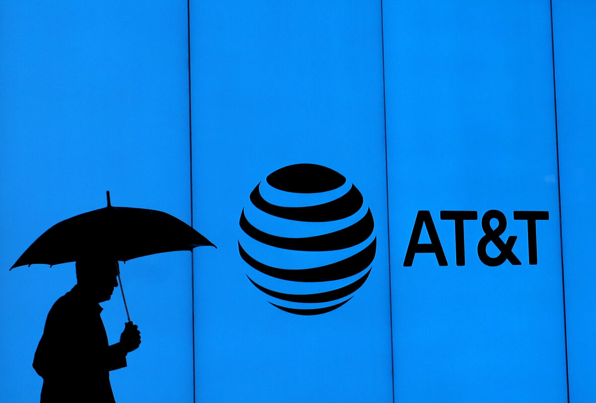 A man walks with an umbrella outside of AT&T corporate headquarters in Dallas, Texas, on March 13, 2020. (Ronald Martinez/Getty Images)