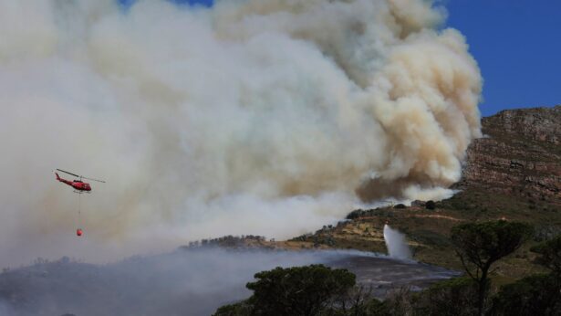 A helicopter drops water over a fire at Rhodes Memorial on Table Mountain, Cape Town, South Africa, on April 18, 2021. (Nardus Engelbrecht/AP Photo)