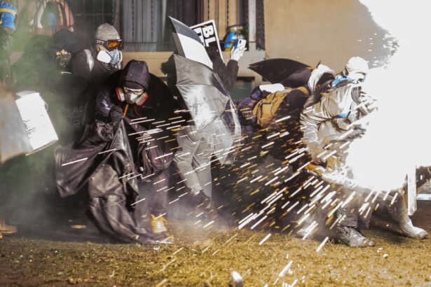 Demonstrators take cover from crowd-dispersal munitions outside the Brooklyn Center Police Department in Brooklyn Center, Minn., late April 13, 2021. (John Minchillo/AP Photo)