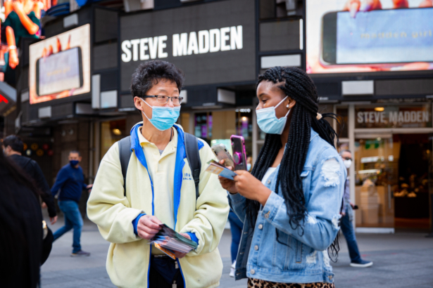 Bystanders watch a parade by practitioners of the spiritual discipline Falun Gong in New York on May 13, 2021. (Chung I Ho/The Epoch Times)