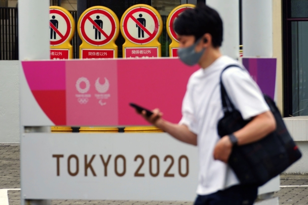A man walks past a banner for the Tokyo 2020 Olympic and Paralympic Games in Tokyo, on May 11, 2021. (Eugene Hoshiko/AP Photo)