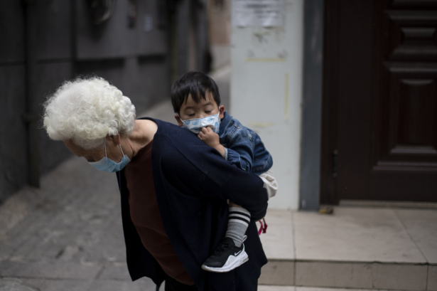 An elderly woman carries a boy on a street in Beijing on May 11, 2020. (NOEL CELIS/AFP via Getty Images)