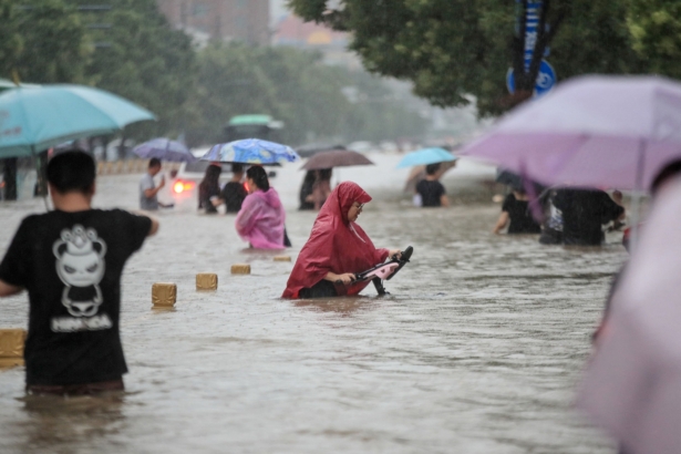 People are wading through floodwaters along a street following heavy rains in Zhengzhou in central China's Henan Province on July 20, 2021. (STR/AFP via Getty Images)
