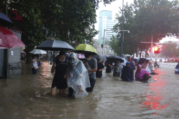 People move through flood water after a heavy downpour in Zhengzhou city, central China's Henan province on July 20, 2021. (Chinatopix Via AP)