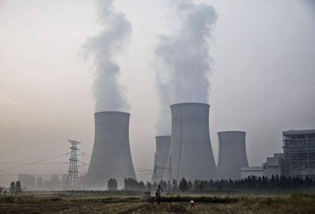 A Chinese farmer works his field next to a state-owned, coal-fired power plant in Huainan, Anhui province, China, on June 15, 2017. (Kevin Frayer/Getty Images)