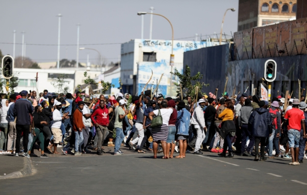 Stick-wielding protesters march through the streets in Johannesburg, South Africa, on July 11, 2021. (Sumaya Hisham/Reuters)