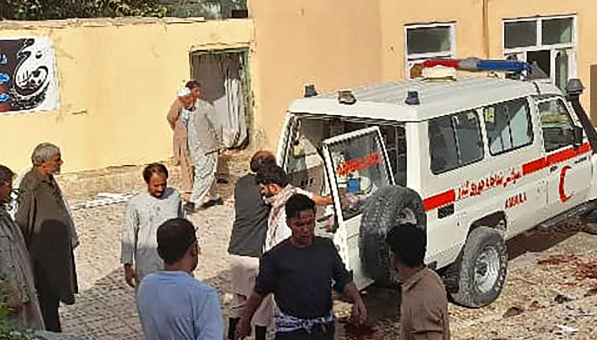 Afghan men stand next to an ambulance after a bomb attack at a mosque in Kunduz, Afghanistan, on Oct. 8, 2021. (AFP via Getty Images)