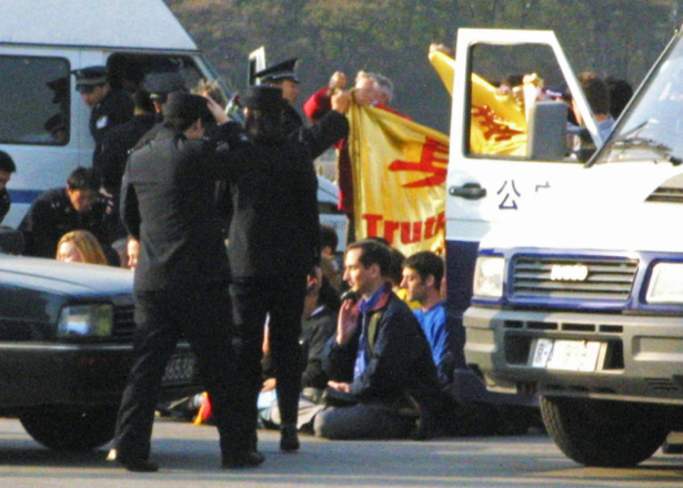 Westerners are surrounded by Chinese police officers and police vehicles in Tiananmen Square after unfurling a pro Falun Gong banner and sitting in a meditation position on Tuesday, Nov. 20, 2001. The group was later taken away and detained by police. (AP Photo/Ng Han Guan)