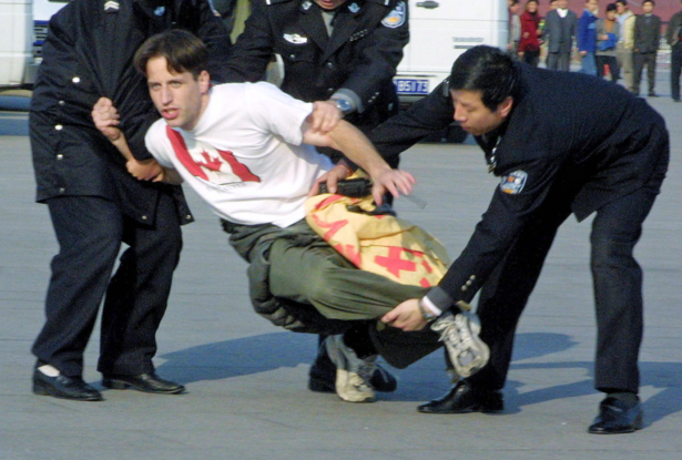 Zenon Dolnyckyj, wearing a T-shirt with a Canadian flag, is wrestled down by Chinese police officers in Tiananmen Square after participating in a sit-in demonstration in support of Falun Gong, on Nov. 20, 2001. (AP Photo/Ng Han Guan)