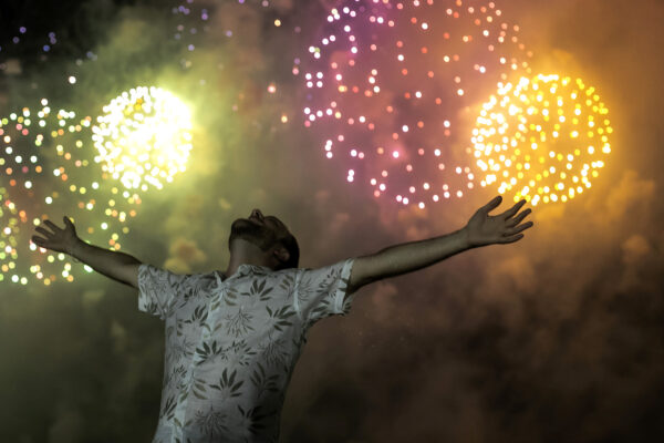 A man celebrates the start of the New Year, backdropped by fireworks exploding in the background over Copacabana Beach in Rio de Janeiro, Brazil, on Jan. 1, 2022. (Bruna Prado/AP Photo)
