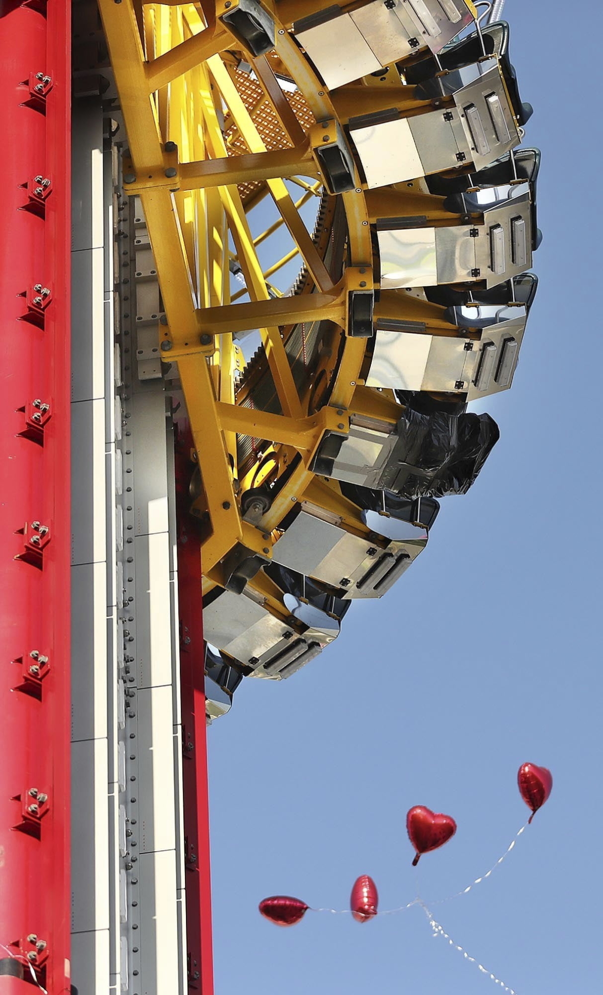 Heart-shaped balloons drift under the seats of the Orlando Free Fall drop tower in ICON Park in Orlando, Fla., on March 28, 2022. (Stephen M. Dowell/Orlando Sentinel via AP)